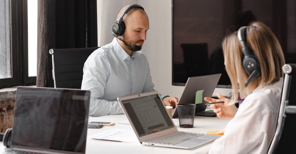 Customer support agents working together with laptops and headsets in an office setting.